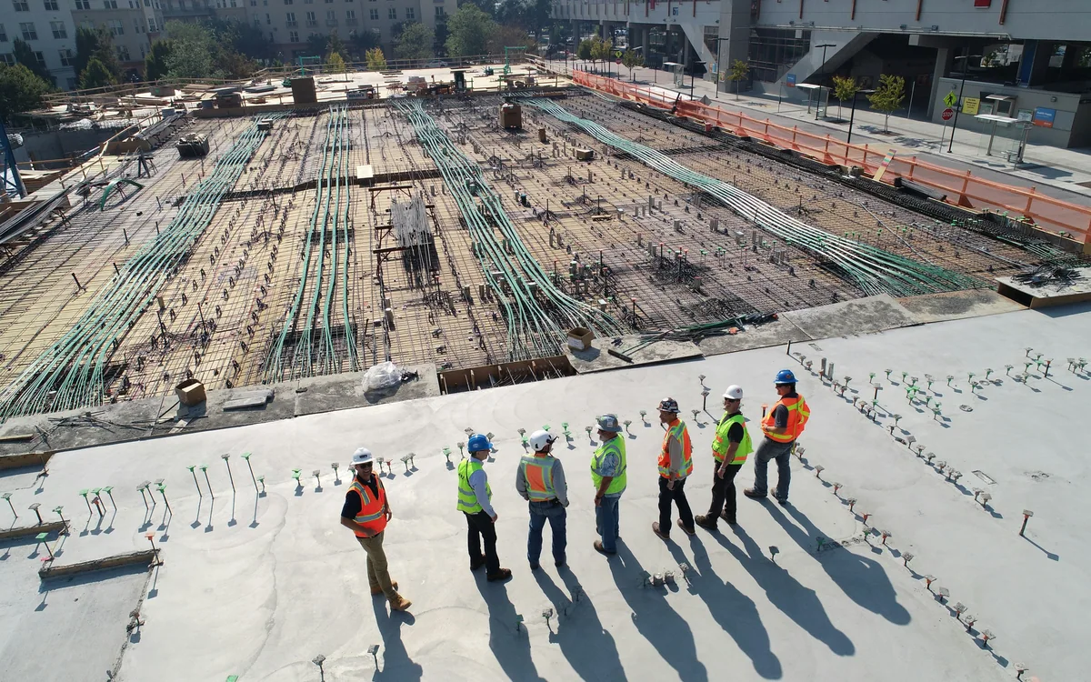 Trabajadores con cascos y chalecos de seguridad en una obra de construcción.