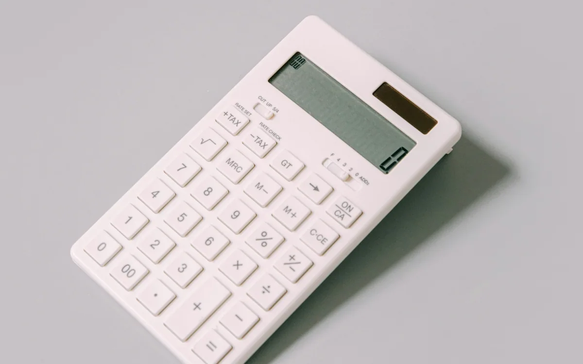Detalle de una calculadora blanca sobre una superficie neutra.
